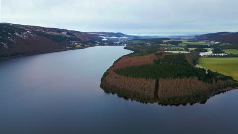 Panorámica-Hacia-La-Izquierda-A-Lo-Largo-De-La-Orilla-Del-Lago-Ness-Con-Montañas-Cubiertas-De-Nieve-Al-Fondo