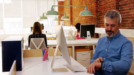 Male-executive-using-smartwatch-at-desk