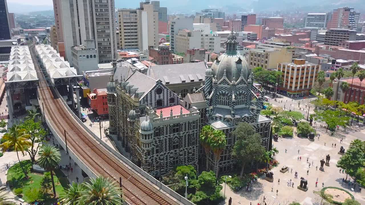 Tomada aérea orbital 4K da Plaza Botero e do metrô em um dia de verão em Medellín