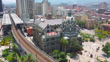 Umlaufende-4K-Luftaufnahme-Der-Plaza-Botero-Und-Der-U-Bahn-An-Einem-Sommertag-In-Medellin