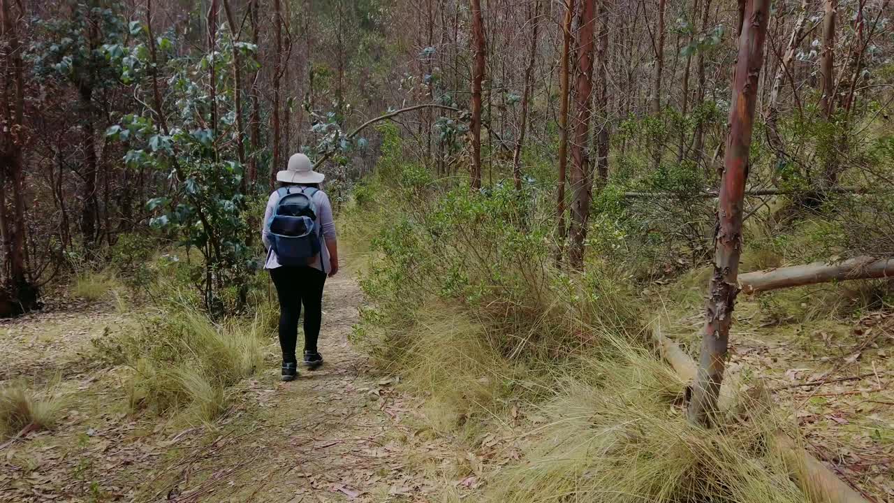 Tracking shot of woman hiking in the surrounding mountains of Cusco, leading from Puka Pukara ruins to Inkilltambo and Rumiwasi ruins during the day