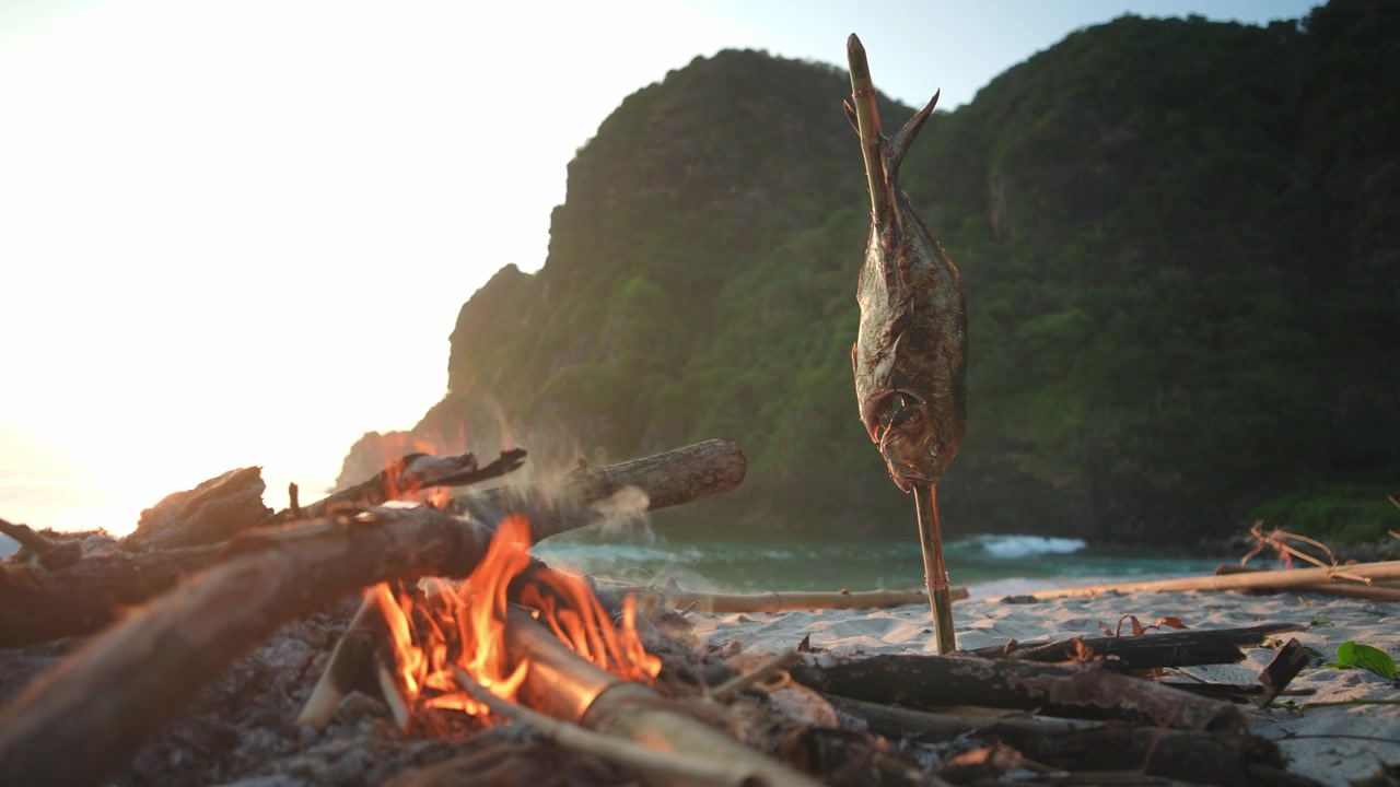 Falò sulla spiaggia che cucina un grande carango con un metodo tradizionale