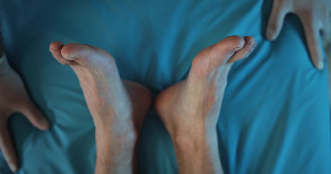 Primo piano di piedi umani che riposano su un lenzuolo blu