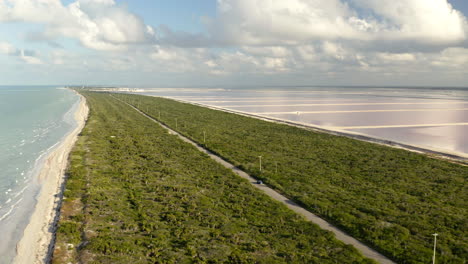 Car-driving-on-road-along-Caribbean-coastline-and-salt-ponds-in-Mexico