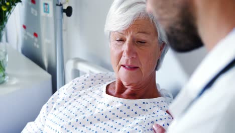 male doctor discussing medical report with senior woman on digital tablet