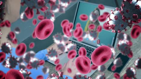 Animation-of-covid-19-cells-and-red-blood-cells-over-businesswoman-on-laptop-video-call