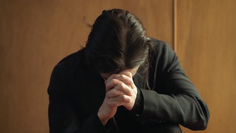 Young-man-in-old-church-building-in-front-of-stained-glass-window-kneeling,-praying,-worshipping