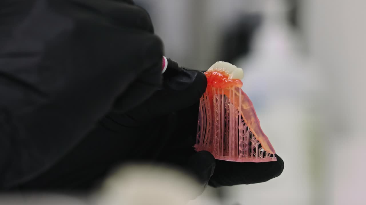 치과 의사는 가짜  이빨의 모델에 미세한 세부 사항을 추가하고 있습니다.