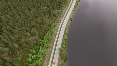hermosa toma panorámica con drones de una calle tranquila en noruega, con hermosos árboles verdes y un lago tranquilo en un día de verano nublado