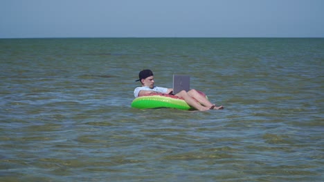 a young business person is enthusiastically working behind a laptop swaying on the waves of sea