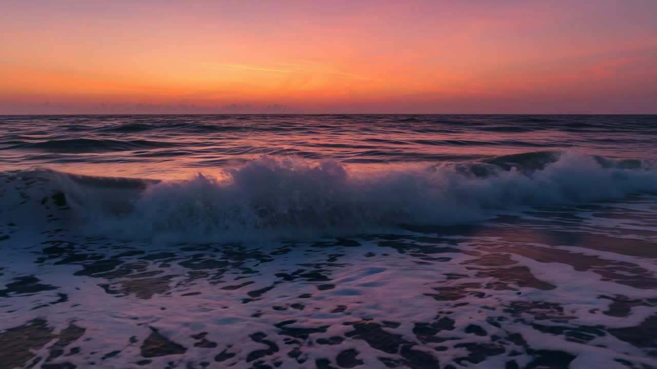 Rolling small swells curving, breaking and receding at shoreline under dusk sky, with foamy crests