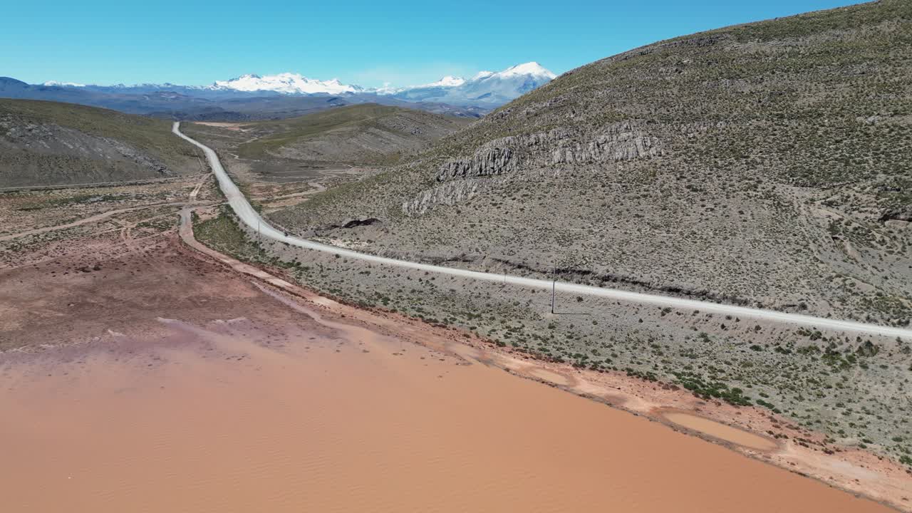 Moto rides dirt highway past muddy Laguna Llajuapampa in Peru mountains