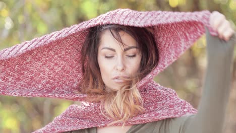 a beautiful brunette model poses with a knit hood scarf outdoors