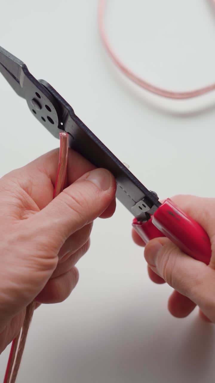 Man stripping two wires with wire strippers. Close up