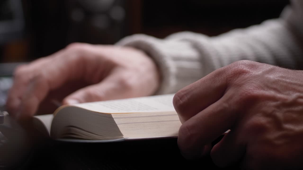 Unrecognizable person reading a book. Hand Turning Pages of a Book, close up.