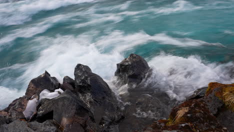 Medium-shot-of-water-flood-crashing-against-rocks-on-shore