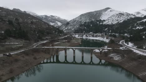 iced mountain peaks river reflected water between valley reservoir of barrios de luna in leon , spain