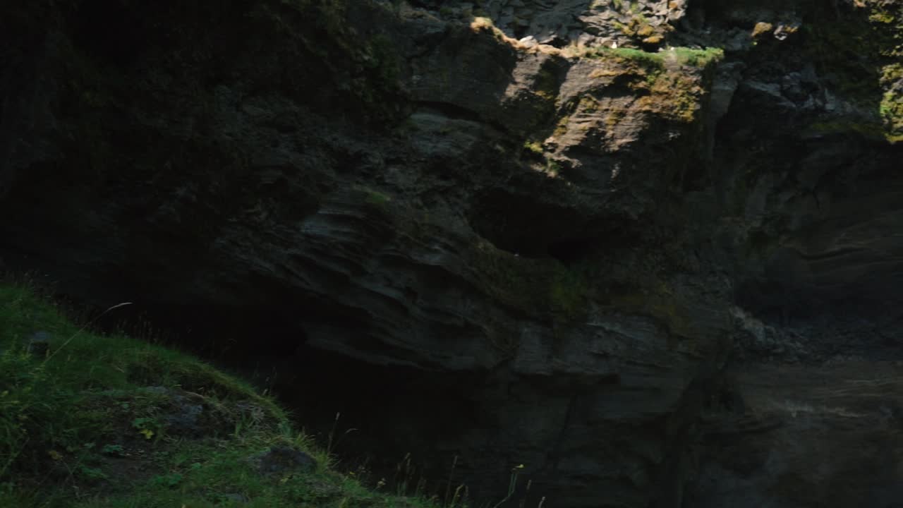 hombre tocando la guitarra frente a una hermosa cascada en islandia