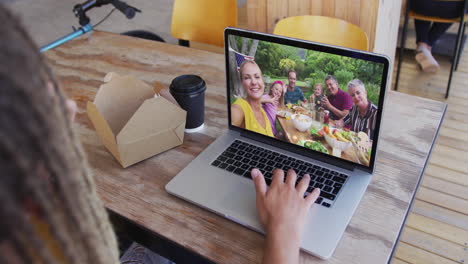 hombre biracial sentado en un café usando una computadora portátil haciendo una llamada de video con la familia