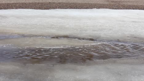 a stream of water flowing down hill in a bank of ice next to a road