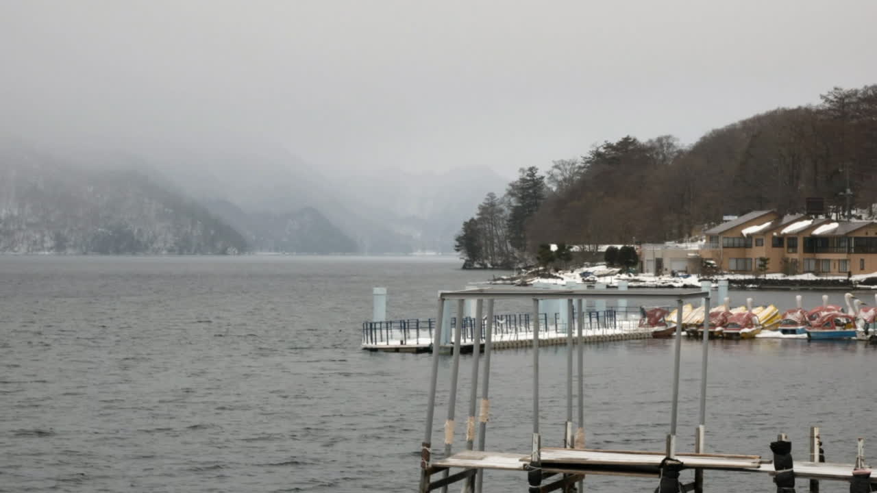 Timelapse of gray choppy water and snow laden clouds blowing across lake Chūzenji, Japan