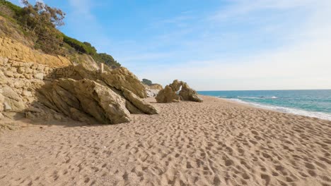 Schöner-Mediterraner-Sandstrand,-Maresme-Barcelona,-San-Pol-De-Mar,-Mit-Felsen-Und-Ruhigem-Meer-Und-Türkis,-Costa-Brava