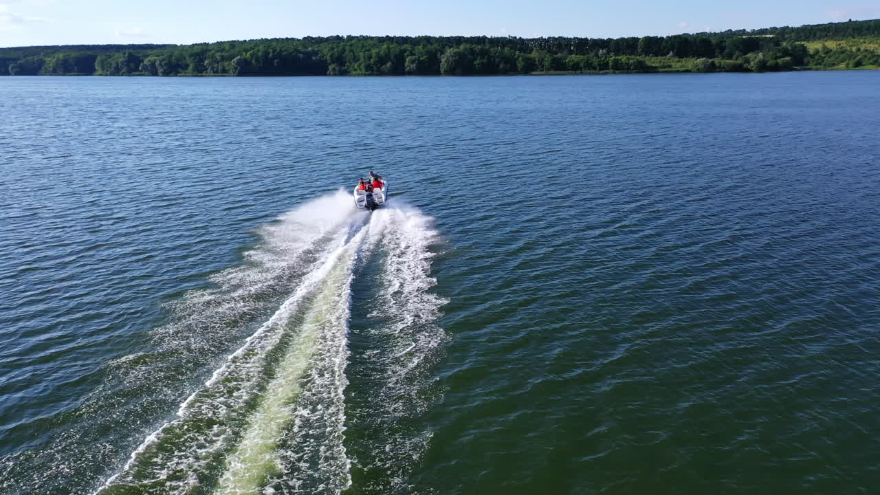 Motor boat rushes along the river. Beautiful view of white foam on blue river water behind the boat on nature background. Aerial view.