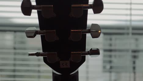 black guitar neck with silver tuning mechanism by the window