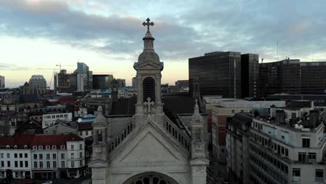 Aerial-upward-flight-from-church-to-city-view-on-cloudy-day-in-Brussels,-Belgium