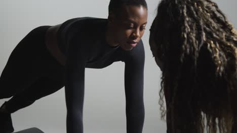 studio shot of two women wearing gym fitness clothing facing each other exercising 1