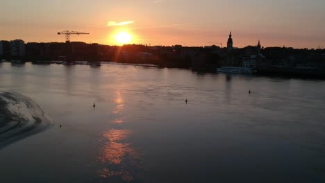 Goldener-Sonnenuntergang-über-Der-Silhouette-Der-Stadt-Mit-Kirchturm-Und-Kran,-Luftbild