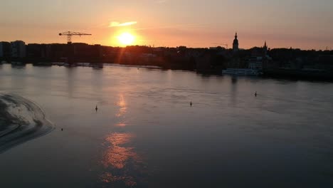 golden sunset over silhouette of city with church tower and crane, aerial view
