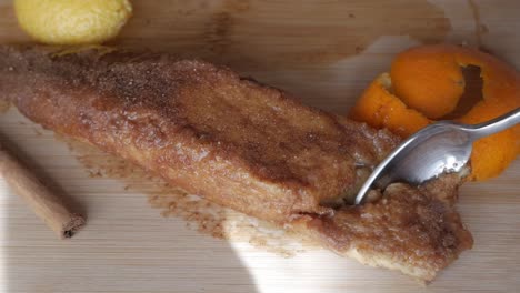 sweet cinnamon-covered torrijas dessert with orange zest and syrup drizzled on top