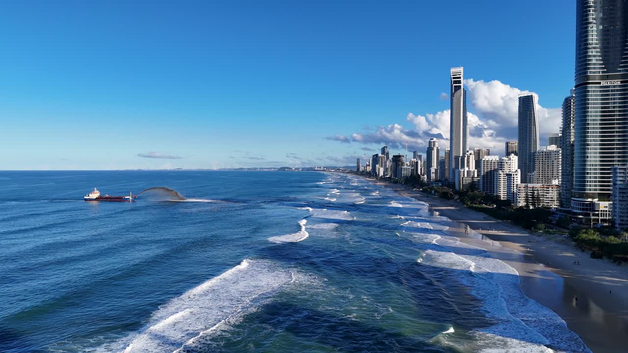 Drone captures sand dredging along Gold Coast shoreline with skyscrapers under clear blue skies
