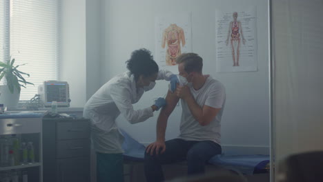 medic making patient vaccine injection in clinic office. doctor vaccinating man.