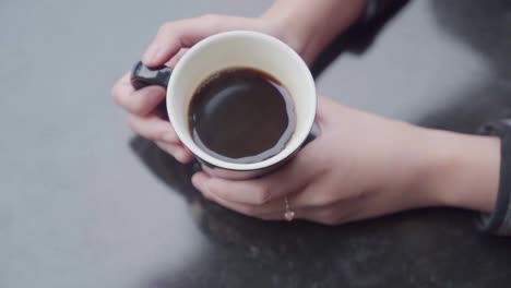 Mujer-En-Un-Café-Al-Aire-Libre-Sosteniendo-Una-Taza-De-Café