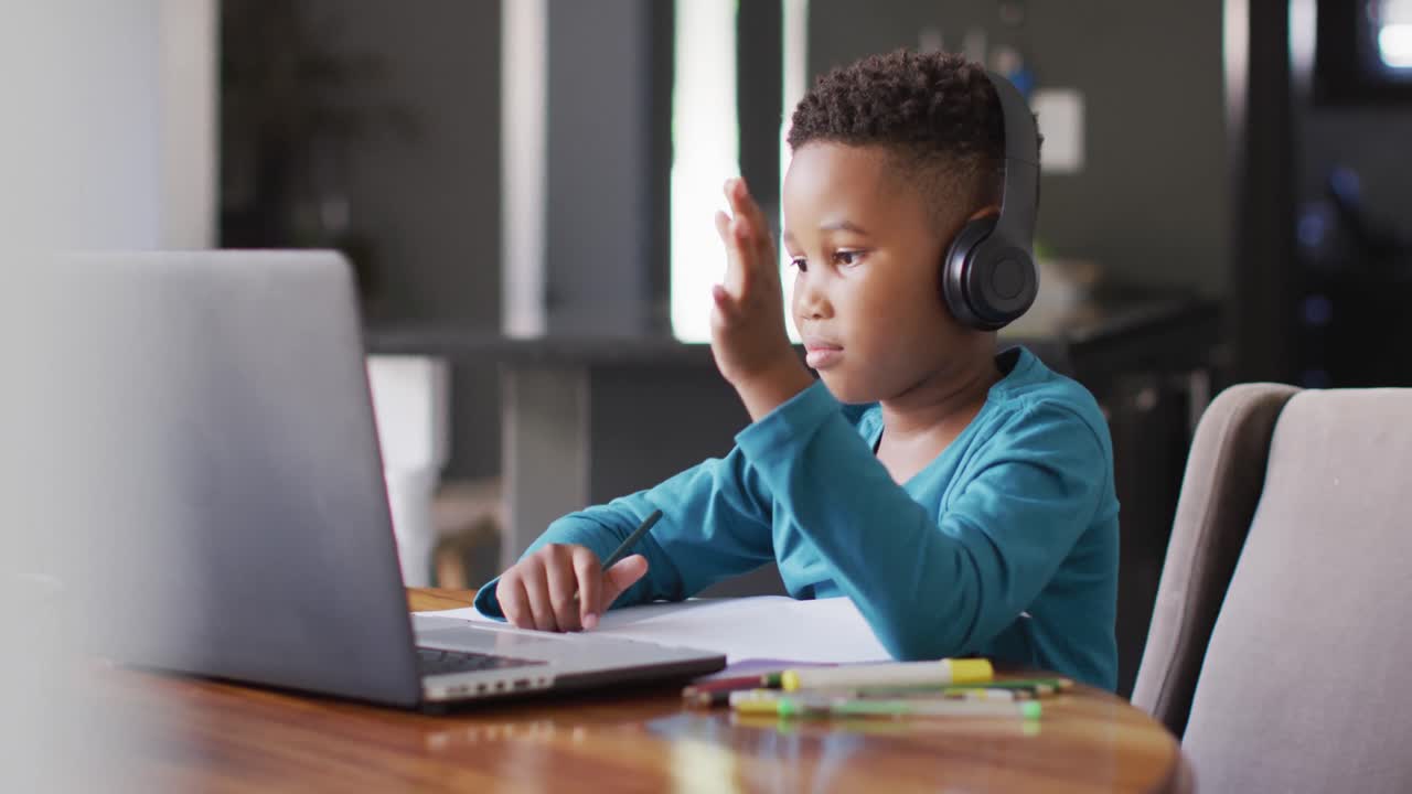 Video of african american boy in headphones learning with laptop
