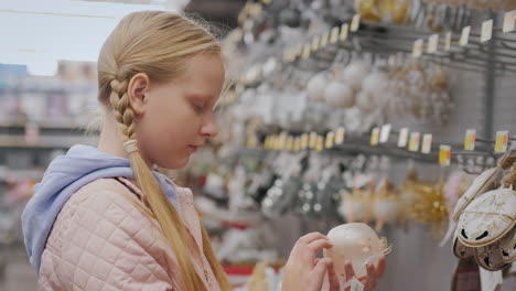 the child chooses decorations for the christmas tree, stands at the showcase with toys in the store