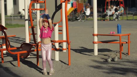 Young-cute-child-girl-in-sportswear-making-fitness-jump-exercises-on-playground.-Workout-for-kids