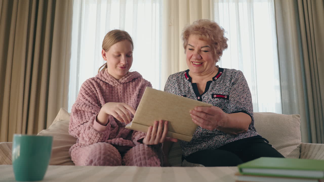 할머니 와 손녀 가 사진 앨범 을 살펴보고 있다