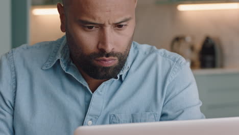 attractive man using laptop working at home browsing online reading email messages on computer enjoying digital communication