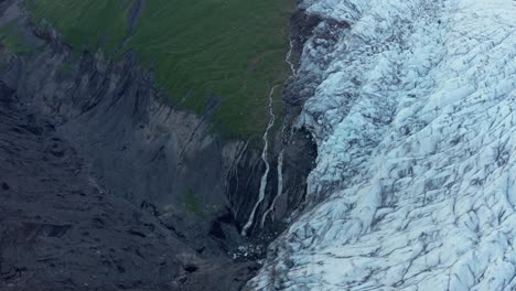 Contrast-in-landscape-between-black-volcanic-mountain-and-white-glacier