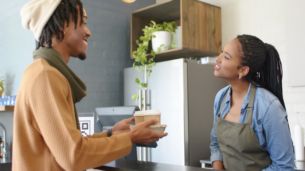 Customer approaching causing female barista placing cups in carrier and accepting cash at cafe