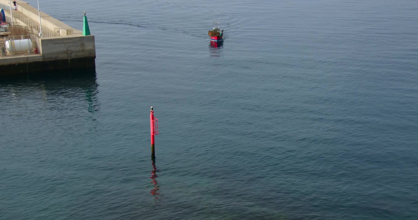 Vidvinkelbilde av en liten fiskebåt som seiler inn i Gamlebyens havn i Puerto del Carmen på Lanzarote