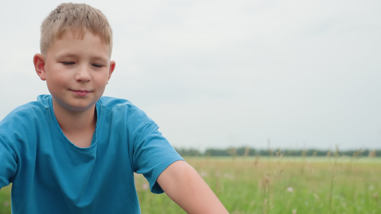 들판에서 자전거를 타며 미소 짓는 백인 남자아이, 핸들바에 꽃이 달린 채 부드러운 미소와 편안한 자세, 탁 트인 수평선과 산들바람, 낙천주의를 전달하는 부드러운 여름 톤, 장난기 넘치는 탐험과 근심 걱정 없는 모습