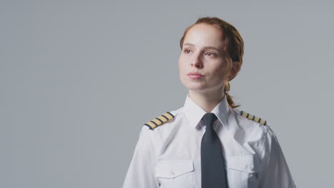 retrato de estudio de una mujer piloto de línea aérea o capitán de barco mirando fuera de la cámara contra un fondo plano