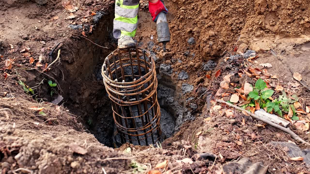 trabajador de la construcción vertiendo cemento líquido de la tubería llenando la excavación de cimientos de hormigón con barras metálicas reforzando la jaula