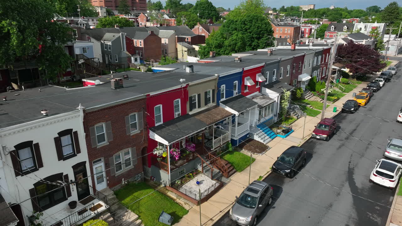 Colorful city homes on beautiful spring day. American infrastructure in large city. Aerial view of rowhouses lining street from angle.