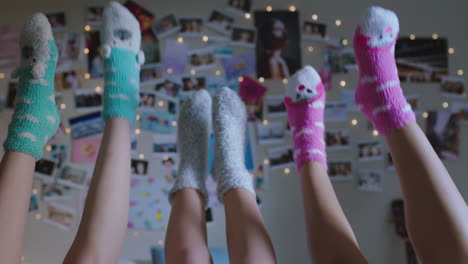 happy teen girls lying on bed at home with legs up having fun wiggling feet hanging out wearing pajamas enjoying relaxing morning on weekend