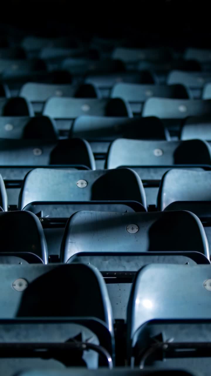 Video verticale: Telecamera panoramica che mostra sedili color ottanio in un'arena, enfatizzando la ripetizione e le inquadrature.